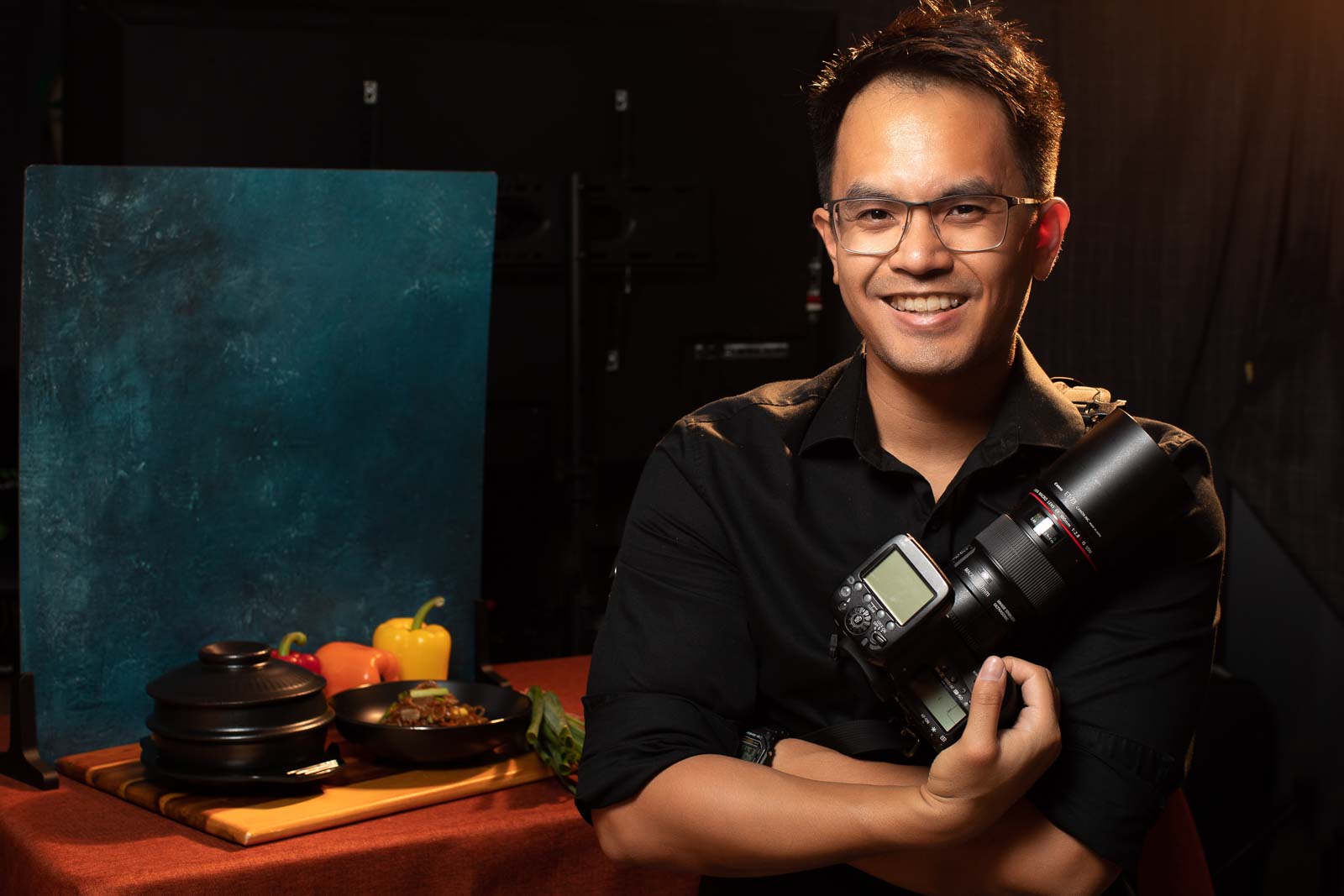 Male holding a professional grade camera in front of a display of meals.